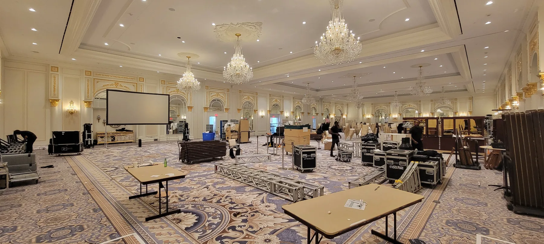 Hotel ballroom mid load-in with LED wall panels being assembled and road cases staged