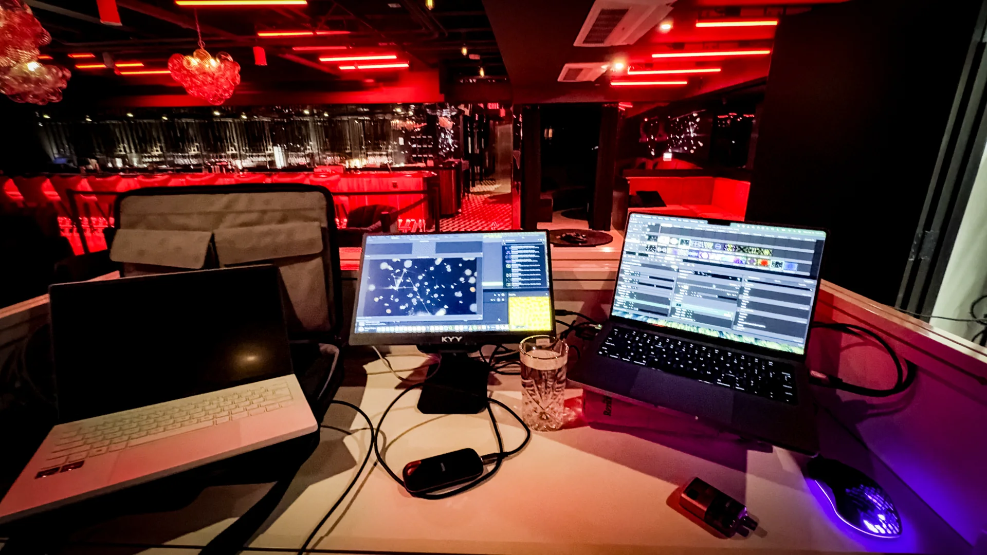 The VJ booth's dual-laptop setup overlooking the red-lit room
