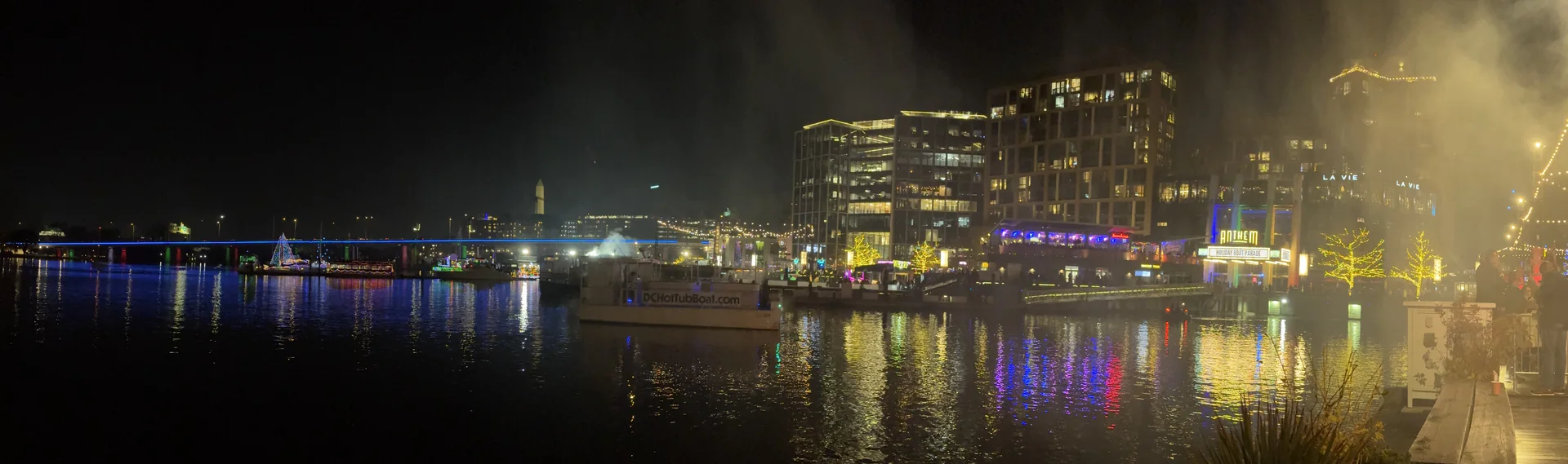 Panoramic night view of the Wharf waterfront with lit buildings and moored boats