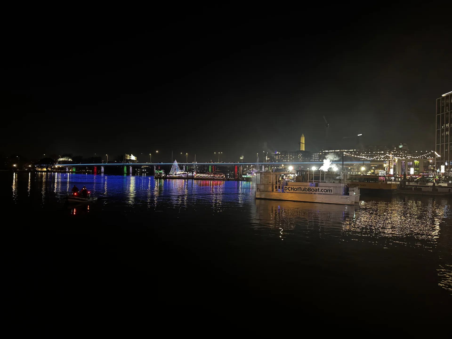 Night view across the channel toward the Washington Monument, with a water taxi at the pier