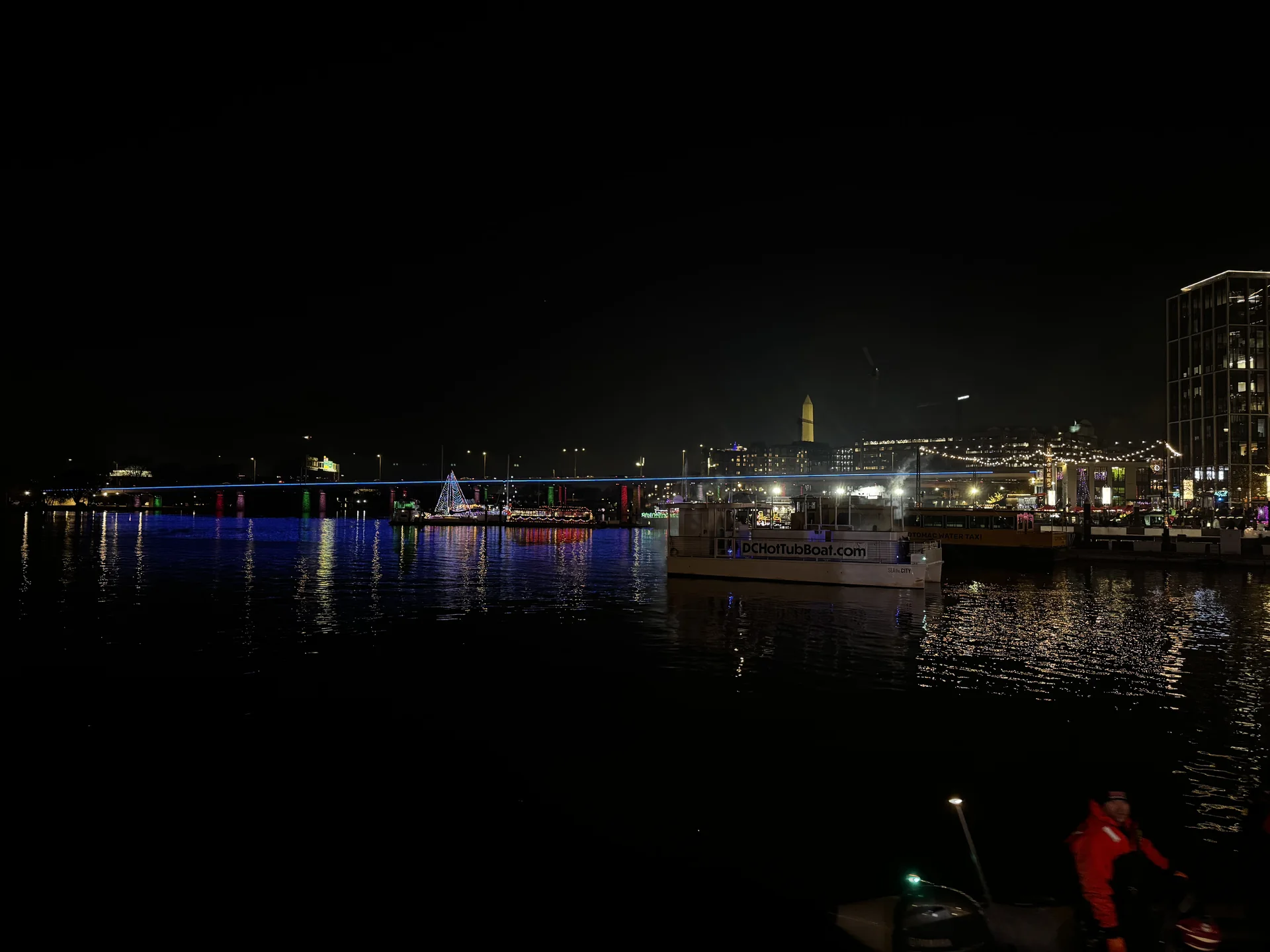 The lit waterfront and channel at night, seen from the pier
