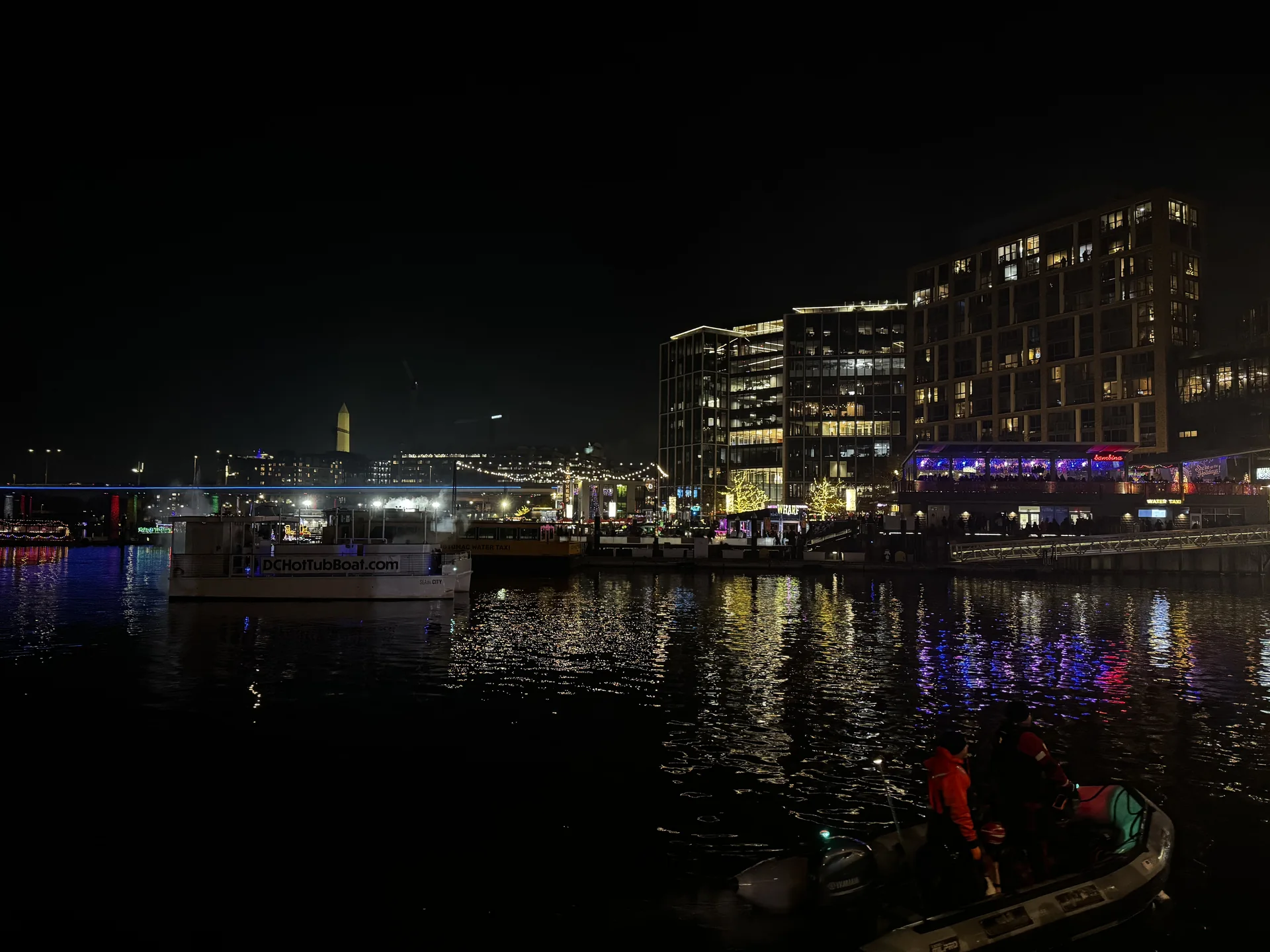 Night waterfront with a safety boat on the channel below the lit buildings