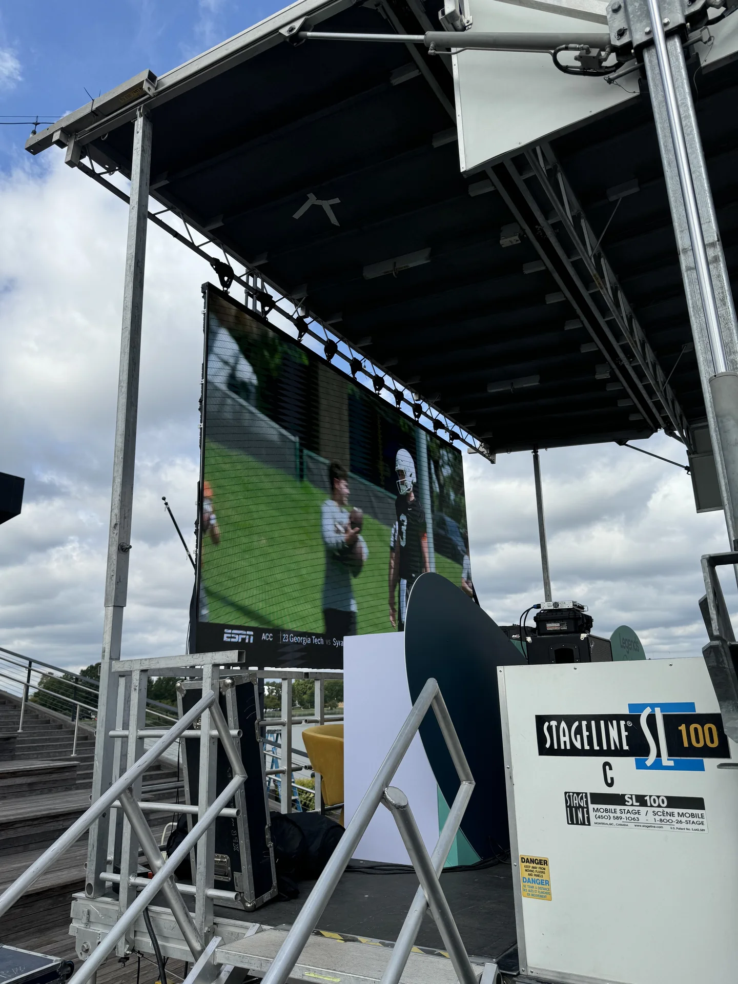 The stage's LED wall showing a live tennis broadcast, seen from the side