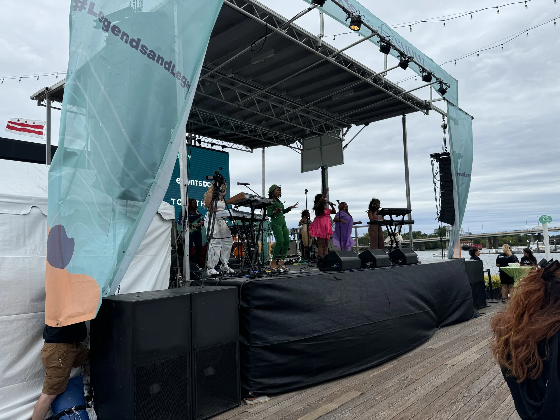 The branded stage front with performers and a seated audience area on the boardwalk