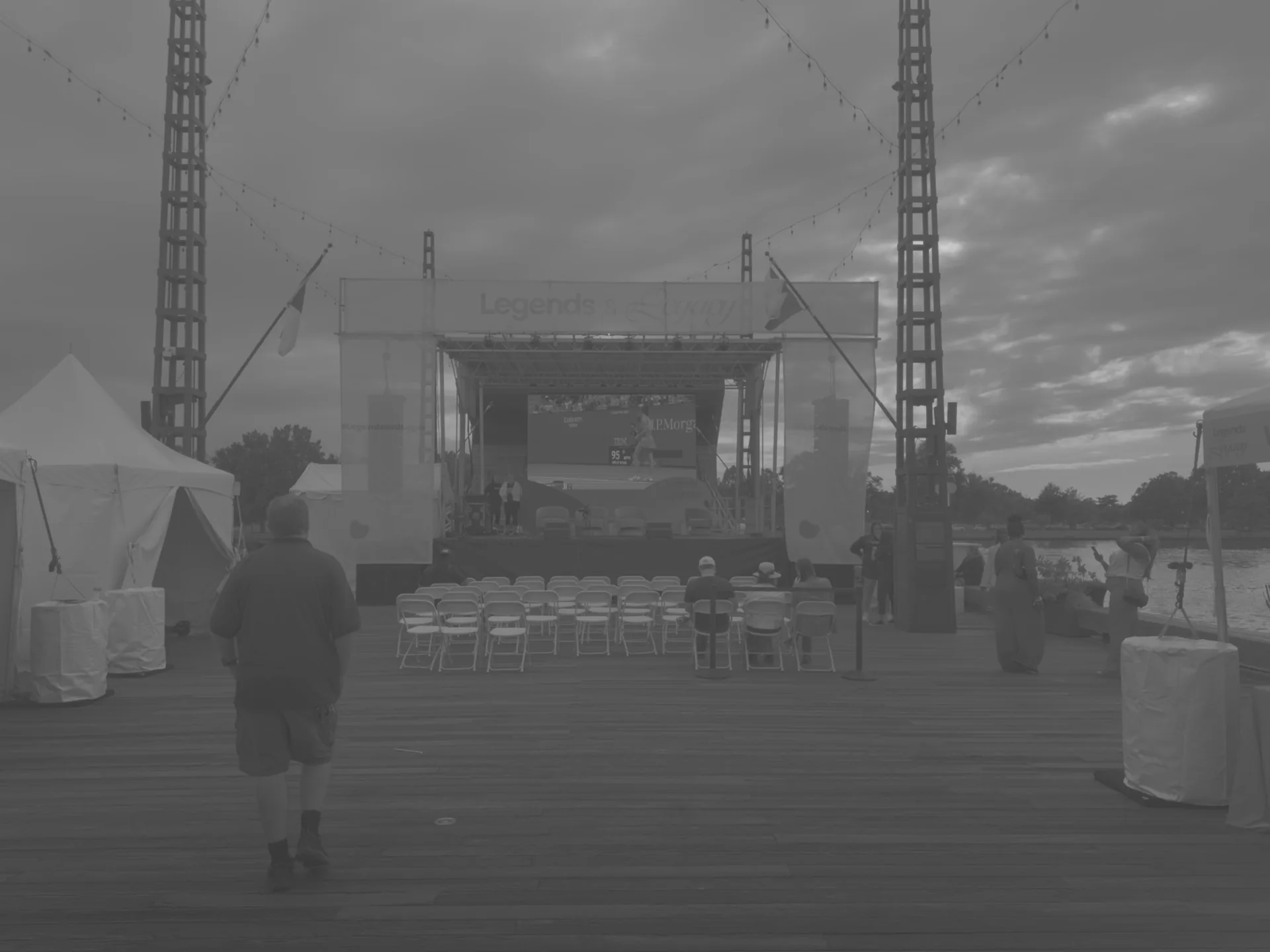 Wide view of the stage with the screen dark, a technician walking away
