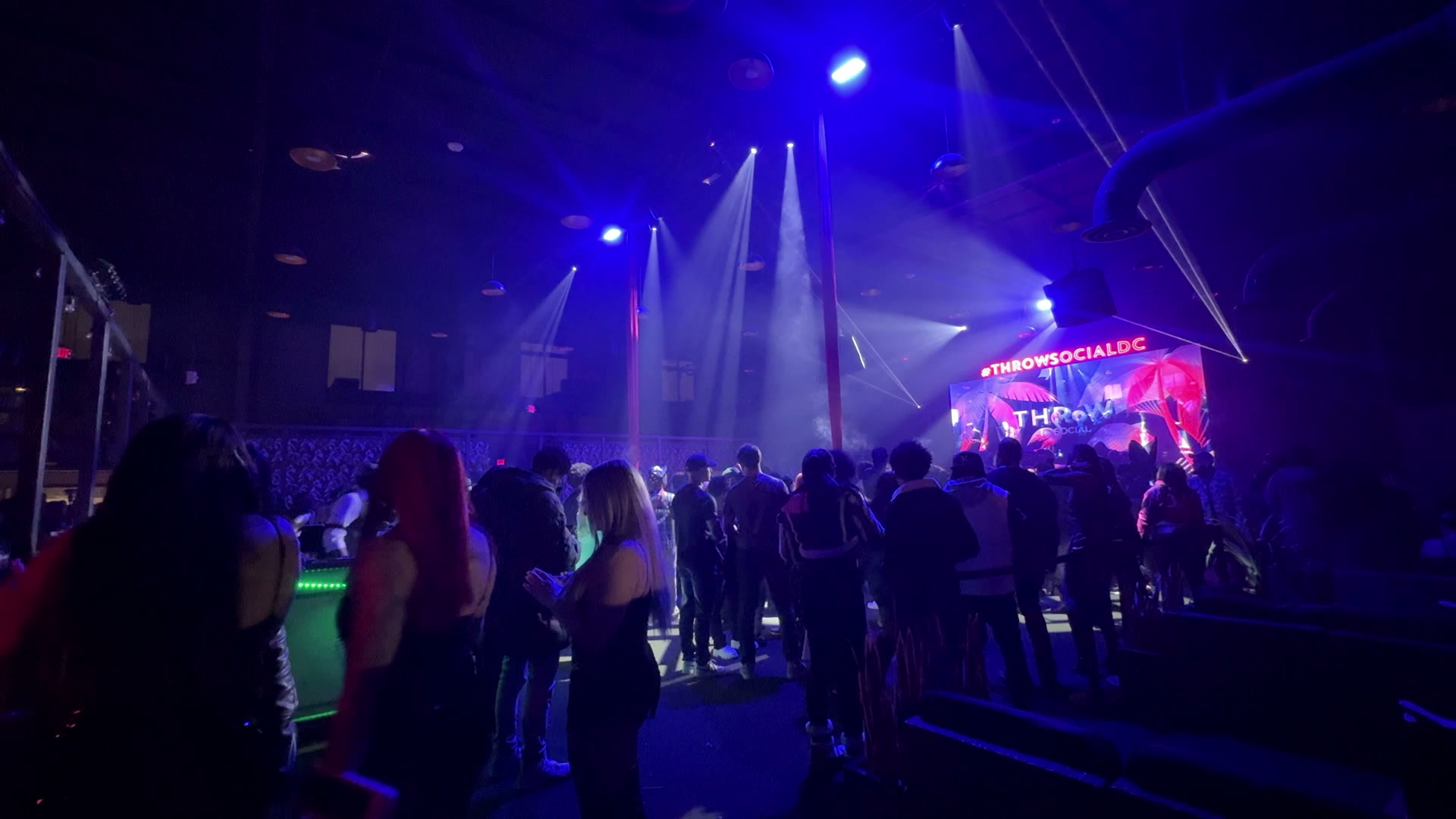 Crowd beneath synchronized video, lighting, and lasers at Throw Social